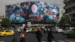 People in Tehran walk past a billboard paying tribute to President Ebrahim Raisi, who died in a helicopter crash last weekend