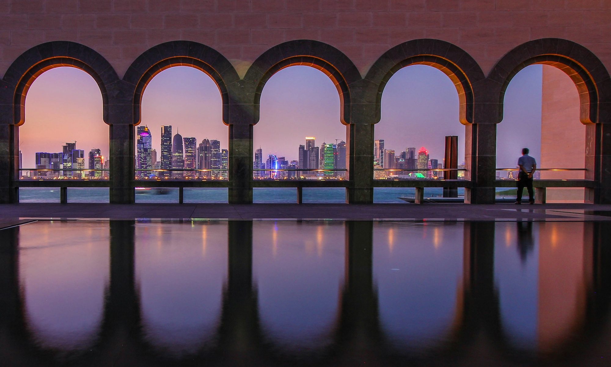 Man looks out at Doha's skyline. Qatar's debt as a percentage of GDP is expected to be just over 37% in 2024