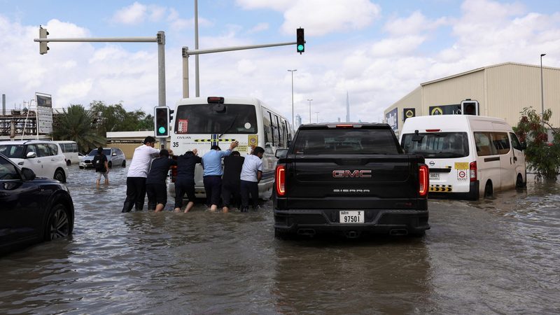 People push a bus through water after heavy rains in Dubai. The emirate's Tasreef flood defence project will take 9 years to complete