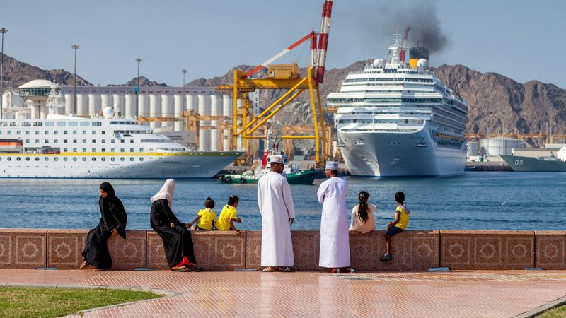 Omanis watch cruise ships in Muscat. Oman's new Social Protection Fund includes benefits for families with children