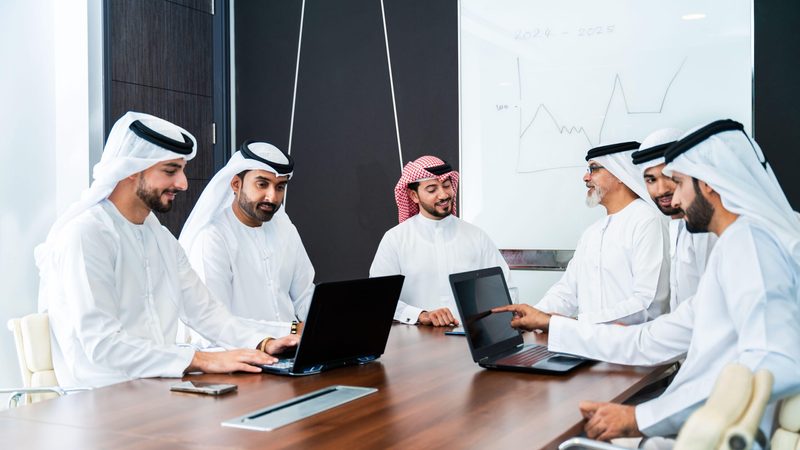 Group of corporate arab businessmen meeting in the office - Middle-eastern businesspeople wearing emirati kandora working in a meeting room, Dubai