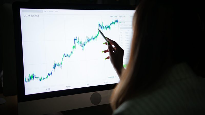 Young Asian broker international stock traders working at night in office using computer and thinking.