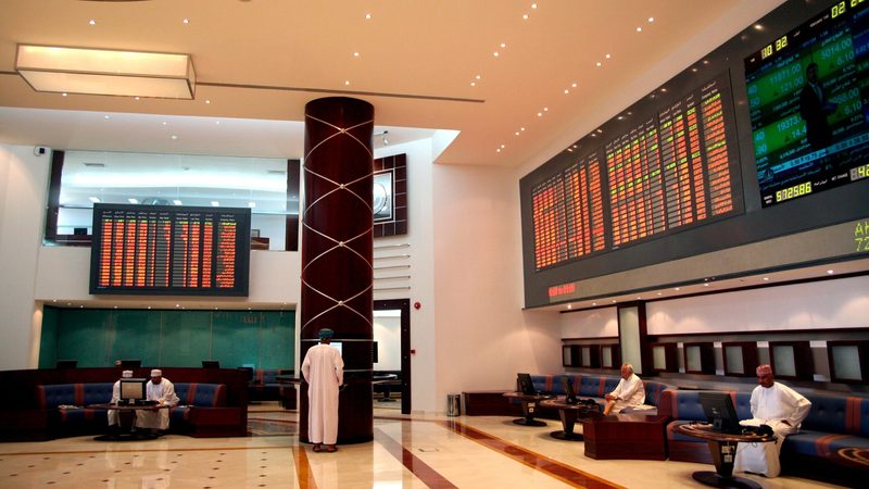 Investors check prices at Oman's stock exchange. OQ Base Industries is due to list in December