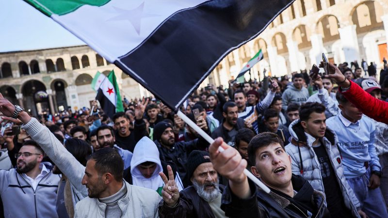 People walk with flags before the first Friday prayers at the Umayyad Mosque in Damascus after the downfall of Assad