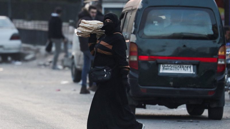 A woman crosses a street in Damascus. In most parts of Syria, electricity is available for just two or three hours a day