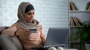 Modern arab housewife typing card number on laptop, banking online, purchase