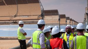 A group of journalists and workers at the construction site for solar thermal power plant in desert