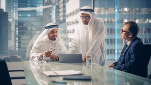 International Business Consultant Advises on Financial Strategy Plan to Successful Arab Company Owners. Multicultural Meeting in Modern Office Between American and Saudi Businessman