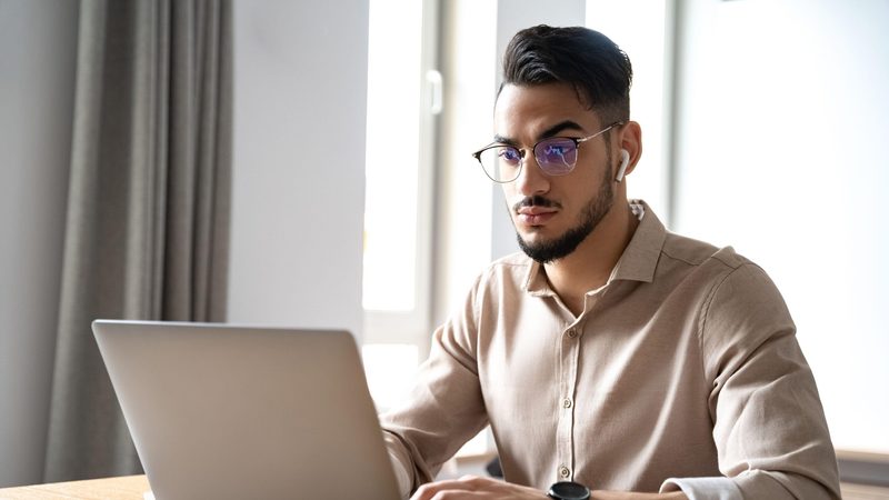 Man works at laptop. Online searches for bitcoin prices more than doubled after President Trump’s post on his Truth Social network