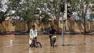 People sitting on bicycles look on amidst flood water following heavy rainfall, in Dubai, United Arab Emirates, April 19, 2024