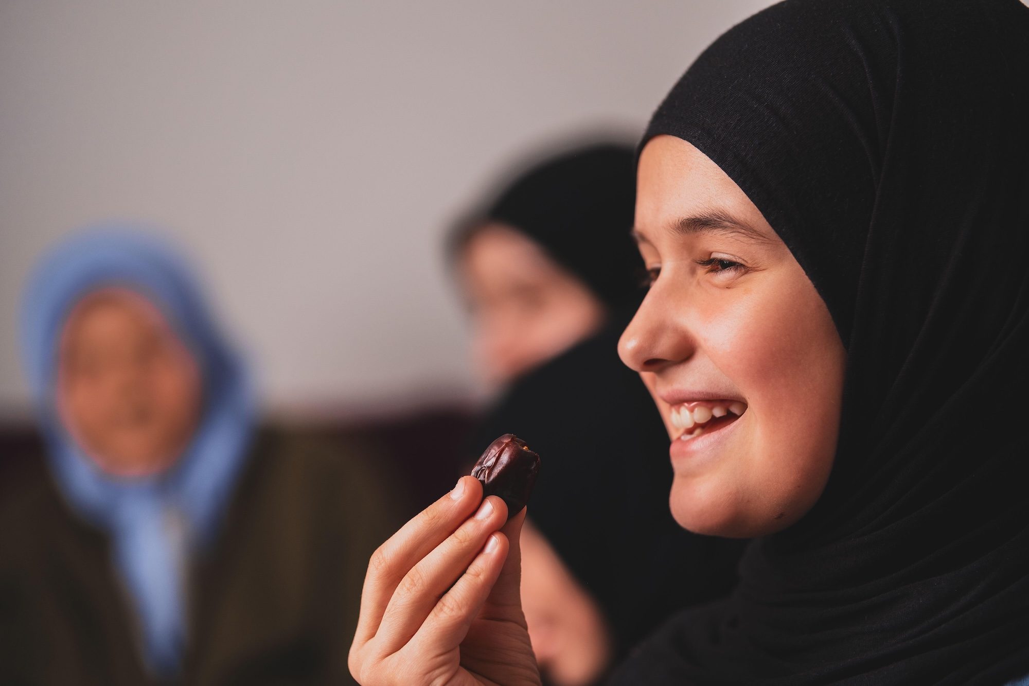 2SRYT40 Happy Muslim family having iftar dinner during Ramadan smiling daughter girl eating dates to break fast eid mubarak.