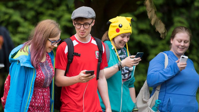 GEB5P2 Pokemon GO players play Pokemon on their mobile phones in parks in Cardiff, South Wales, UK.