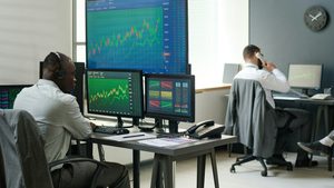 Two men working in finance at computers displaying charts. Derayah Financial CEO Mohammed AlShammas believes its listing will encourage other local and regional players to do the same