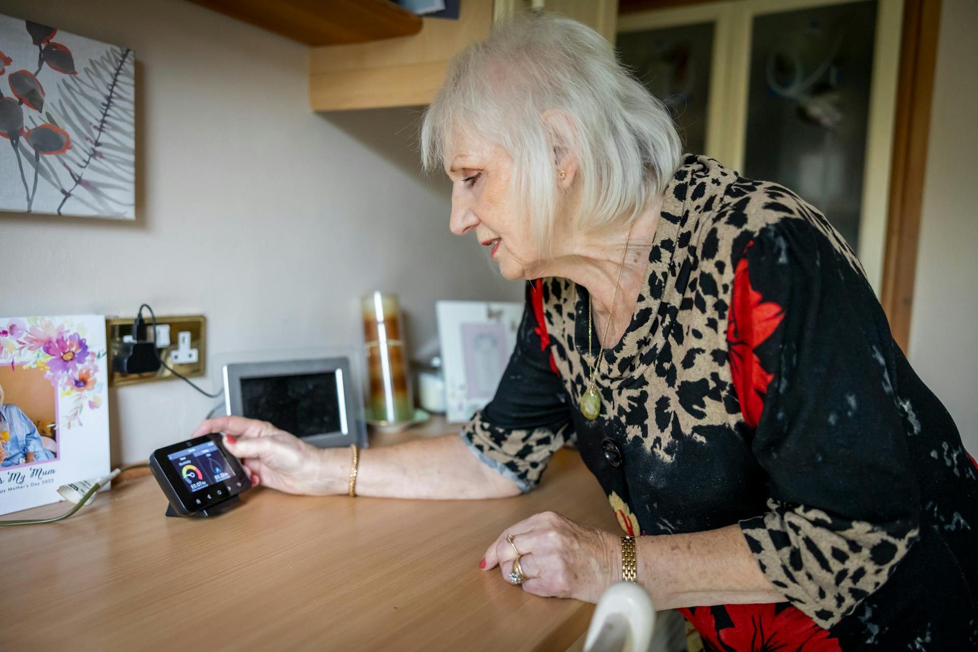 An older white woman checks a smart meter at home. Mubadala says Calisen has an installed base of 16 million smart meters